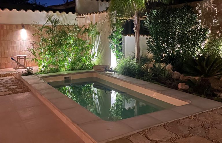Poolpflege Homeservice Hausbetreuung Mallorca Kleiner, geheimer Gartenpool umgeben von Pflanzen und sanfter Beleuchtung. Poolpflege Mallorca
